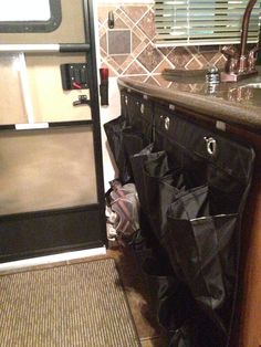 a kitchen area with a sink, counter and black trash bags on the floor next to it