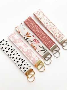 four key fobs are lined up on a white surface, each with different patterns and colors