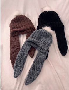 four knitted hats and mittens laid out on a white sheet, one is black, one is brown