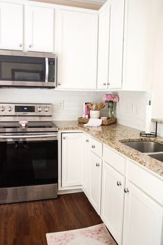 a kitchen with white cabinets and stainless steel appliances