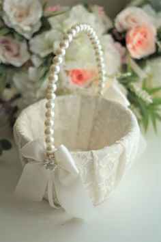 a white basket with pearls and flowers in the background