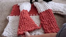 a black and white cat laying on top of a red and white knitted blanket