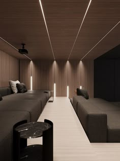 a room with couches, tables and lamps on the ceiling is lit by recessed lights