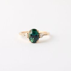 an oval green and white diamond ring on a white surface with the top half cut off