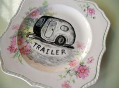 a white plate with a trailer painted on it's side and flowers around the edge