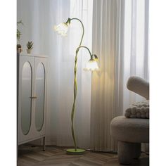 a floor lamp with three lights on it in front of a white curtained window