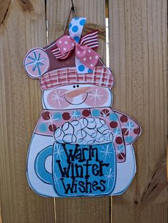 a wooden fence with a sign that says warm winter wishes and a bear holding a mug