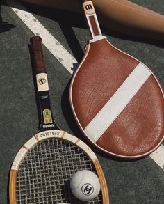 a tennis racket and ball are on the ground next to a bat that is leaning against it