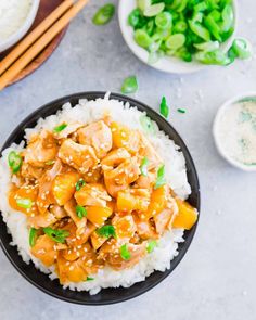 a bowl filled with chicken and rice next to chopsticks on a table top