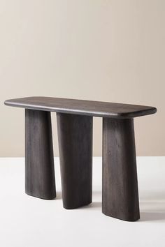 two wooden stools sitting next to each other on a white table with a beige wall in the background