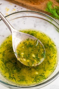 a glass bowl filled with green liquid next to a wooden spoon