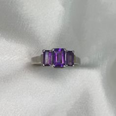 This beautiful three-stone ring showcases three emerald-cut amethyst, each secured in prongs, with a total weight approx of 0.97 carats. The elegant openwork design in the under-gallery adds to its charm. Handcrafted in platinum. The ring measures approximately 10.18mm across from the east and west and has a width of 5.92mm. Currently sized at 5.25 and can be resized at no extra cost. ✦ GEMSTONE SPECIFICATIONS: Center Stone: Amethyst Amethyst Weight: Approx 0.97 Carats Amethyst Cut: Emerald Cut 3 Carat Ring, Vintage Diamond Earrings, 5 Carat Ring, Estate Diamond Jewelry, Emerald Cut Ring, Designer Diamond Jewellery, Colored Diamond Rings, Purple Amethyst Ring, Jewelry Education