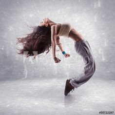 a woman is dancing in the air with her hair blowing back and feet spread out