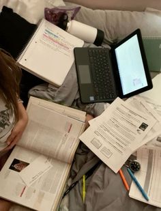 an open laptop computer sitting on top of a pile of papers