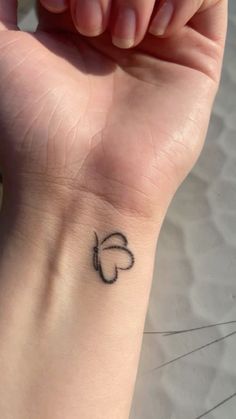 a small black heart tattoo on the wrist