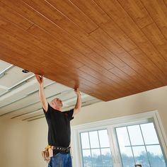 a man is working on the ceiling in his new home with wood planks installed