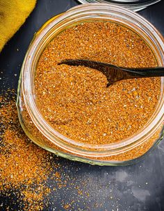 a glass jar filled with spices on top of a black table next to a yellow towel