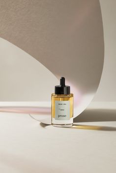 a bottle of perfume sitting on top of a white table next to a curved object