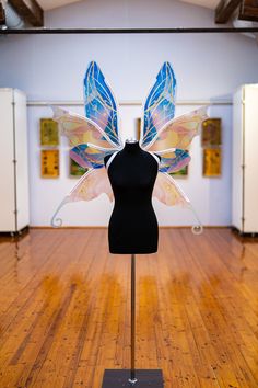 a mannequin wearing a dress form with colorful wings on it's back