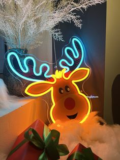 a lighted reindeer head next to presents under a christmas tree