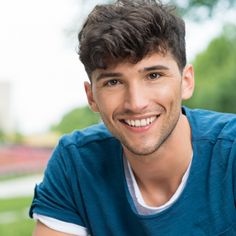 a young man smiling and wearing a blue shirt