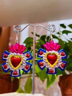 a pair of heart shaped earrings sitting on top of a table next to a potted plant