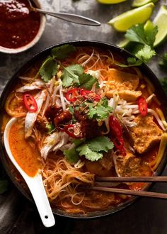 a bowl filled with noodles, meat and veggies on top of a table