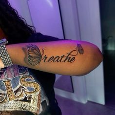 a woman with a butterfly tattoo on her arm that says breathe and butterflies are all around her