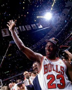 a basketball player holding his hands up in the air with confetti falling around him