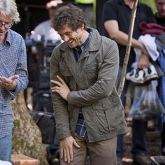 two men standing next to each other in the woods