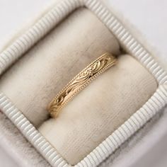 a gold wedding band in a white box