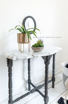 a white table with a plant on top and a mirror above it in the corner