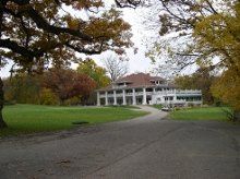 a large white house sitting on top of a lush green field next to a road