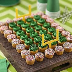 cupcakes with green frosting and sprinkles on a wooden board