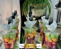 there are many different types of fruit in the glass vases with forks sticking out of them