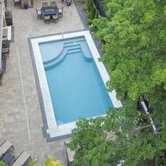 an aerial view of a swimming pool surrounded by trees and patio furniture with chairs around it