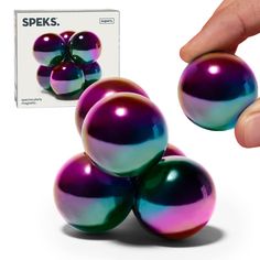 a hand is holding three balls in front of a box that says speks