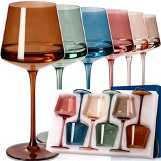 six different colored wine glasses sitting in a box with one empty glass and the other half full