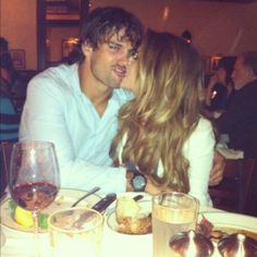 a man and woman sitting at a table kissing