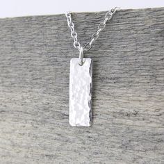 A dainty classic small silver bar necklace. This necklace is specifically created to be just a whisper along your neck line, dainty, delicate, lightweight and beautiful. Perfect for layering with your favorite pieces.Petite and dainty, this necklace consists of a 5/8 inch Sterling Silver rectangle bar, hammered with my Classic texture and suspended from dainty 1.9mm Sterling Silver cable chain. The pendant is suspended just over 5/8 inch in length from the chain and tumble polished for shine.  P Simple Rectangular Silver Jewelry, Simple Sterling Silver Necklace With Rectangular Pendant, Simple Silver Rectangular Pendant Jewelry, Simple Silver Necklace With Rectangular Pendant, Silver Dainty Bar Necklace For Everyday, Dainty Silver Bar Necklace Gift, Minimalist Silver Bar Necklace As Gift, Elegant Silver Rectangular Bar Necklace, Silver Sterling Silver Bar Necklace With Rectangular Pendant