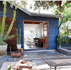 a blue house with cactus and succulents in the front yard, next to an outdoor seating area