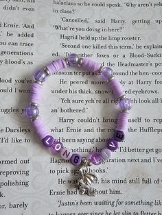 a purple beaded bracelet with an elephant charm on it's end and the word love written in large letters