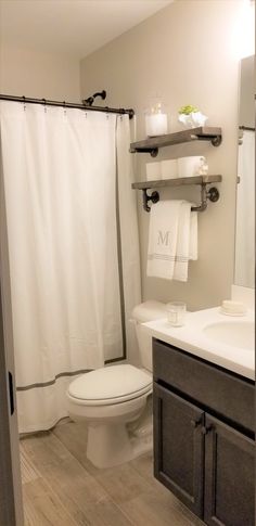 a white toilet sitting in a bathroom next to a sink and bathtub under a shower curtain