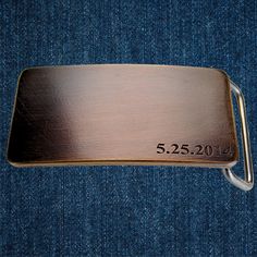 a metal belt buckle with the date 5 25 2011 engraved on it in blue jeans