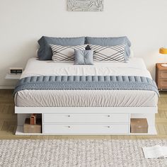 a bed with blue and white pillows on top of it in a bedroom next to a rug