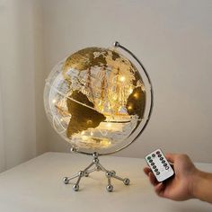 a person holding a remote control next to a small globe with lights on it,