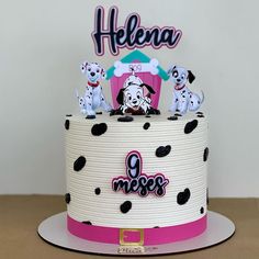 a birthday cake decorated with black and white polka dots has three puppies on top