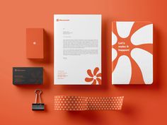 an orange and white stationery set on top of a red surface with a padlock