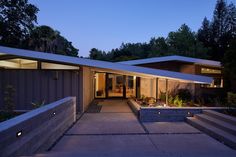 the entrance to a modern home at night with lights on and steps leading up to it