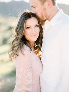 a man and woman standing next to each other in front of the camera with their arms around each other